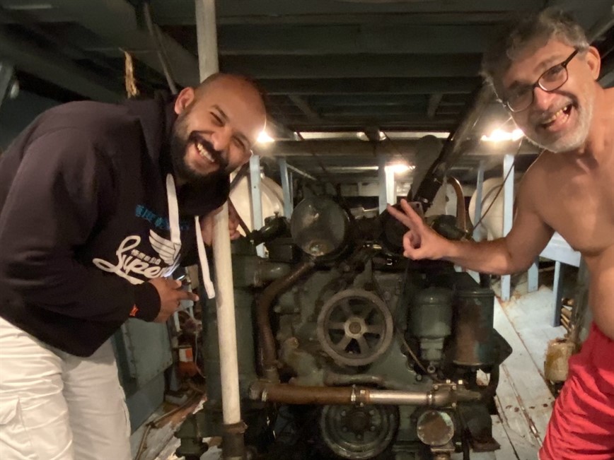 Picture of two assessors standing next to a boat engine. 