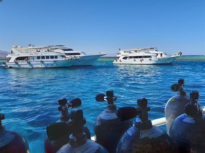 Picture of boats on the sea in Egypt. There are scuba tanks in the foreground. 