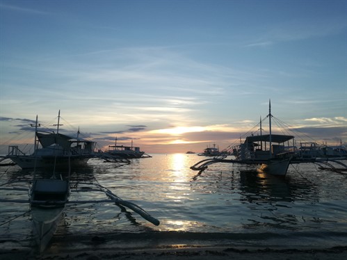 Picture of diving boats on the ocean with a sunset in the background. 