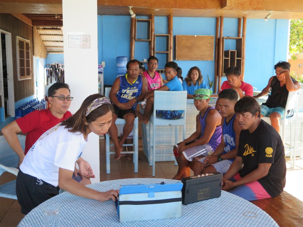 Picture of the Green Fins Philippines team having a meeting. A group of people is sitting around a laptop. 