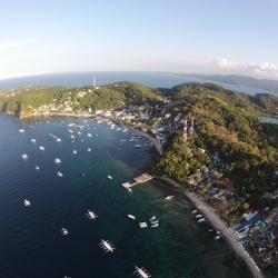 Picture of the ocean and shoreline in Puerto Galera, showing lots of boats in the water. 