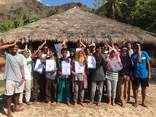 Picture of a group of people holding certificates and making a fin sign with their hands. 