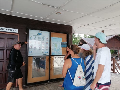 Picture of a Scuba Junkie instructor talking a group of people through the Green Fins guidelines. 