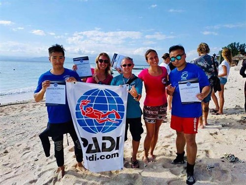 A picture of divers from Legend Diving Lembongan on the beach holding a PADI flag