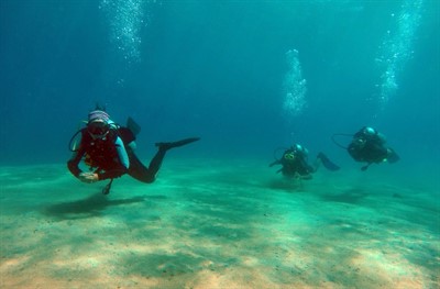 Picture of three SCUBA divers at the edge of a reef. 