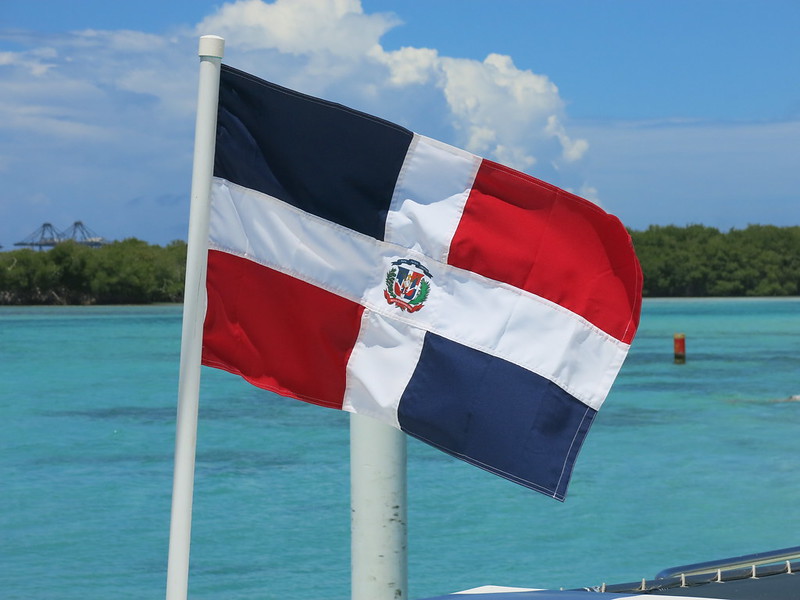 Dominican Republic flag flying with a beach in the background