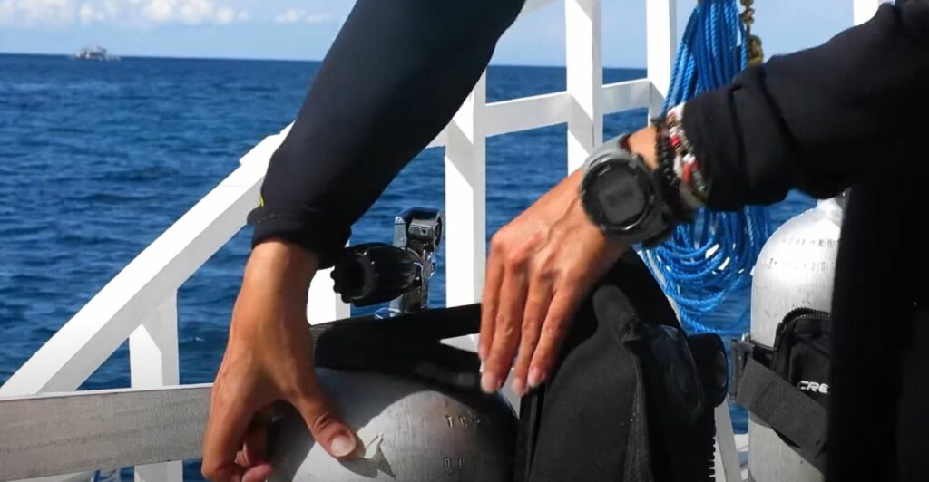 Photo of a diver sticking masking tape to the side of their tank to demonstrate why reusable tank caps are important in preventing marine debris.